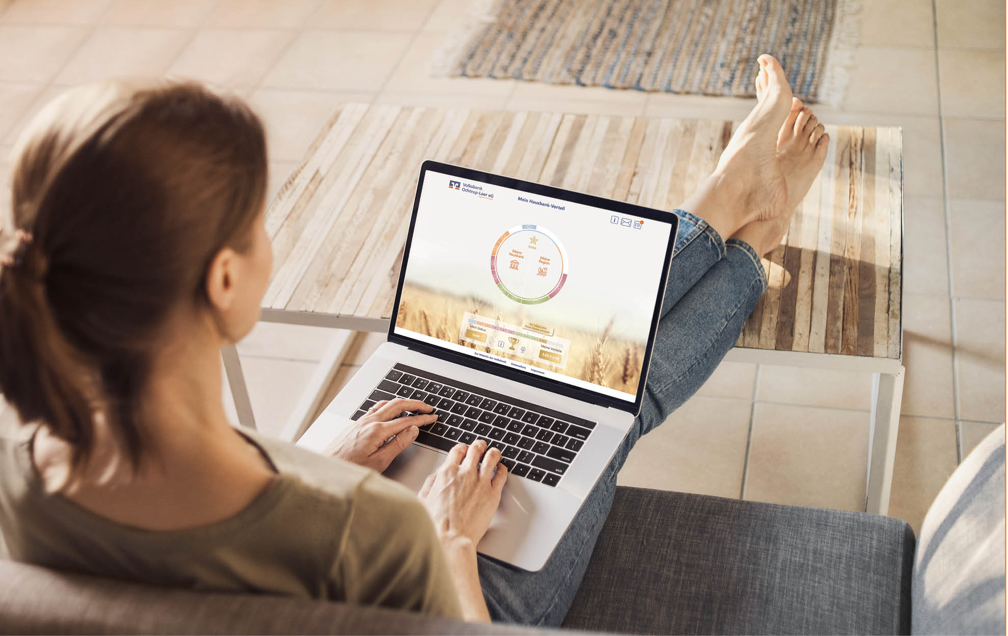 Frau sitzt entspannt auf dem Sofa und nutzt auf ihrem Laptop das digitale Hausbank-Tool der Volksbank mit Kreisdiagramm-Anzeige.