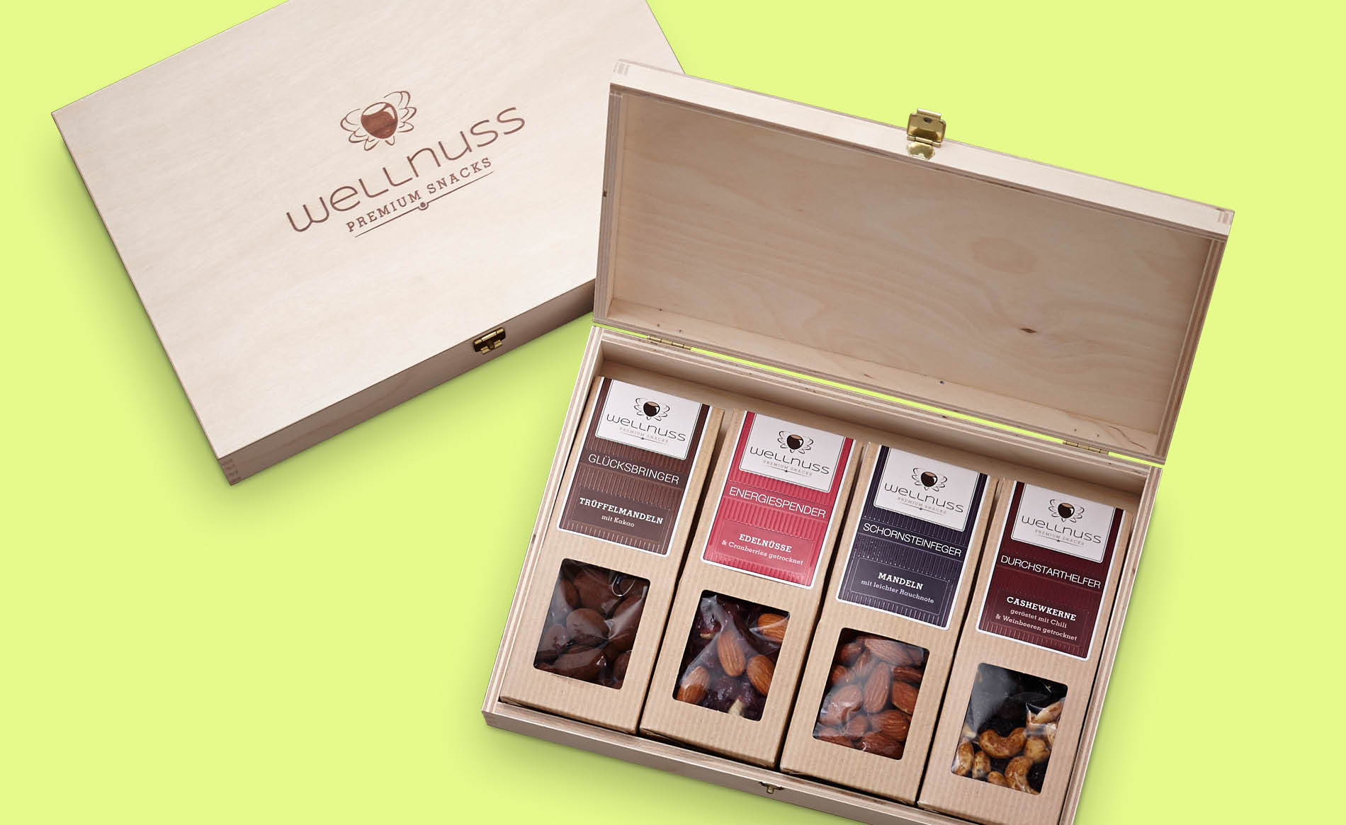 Wellnuss – Verpackungsdesign & Corporate Design Premium-Verpackung von Wellnuss mit edler Holzbox und Snack-Auswahl in Kartonverpackungen – Branding für hochwertige Nussmischungen.